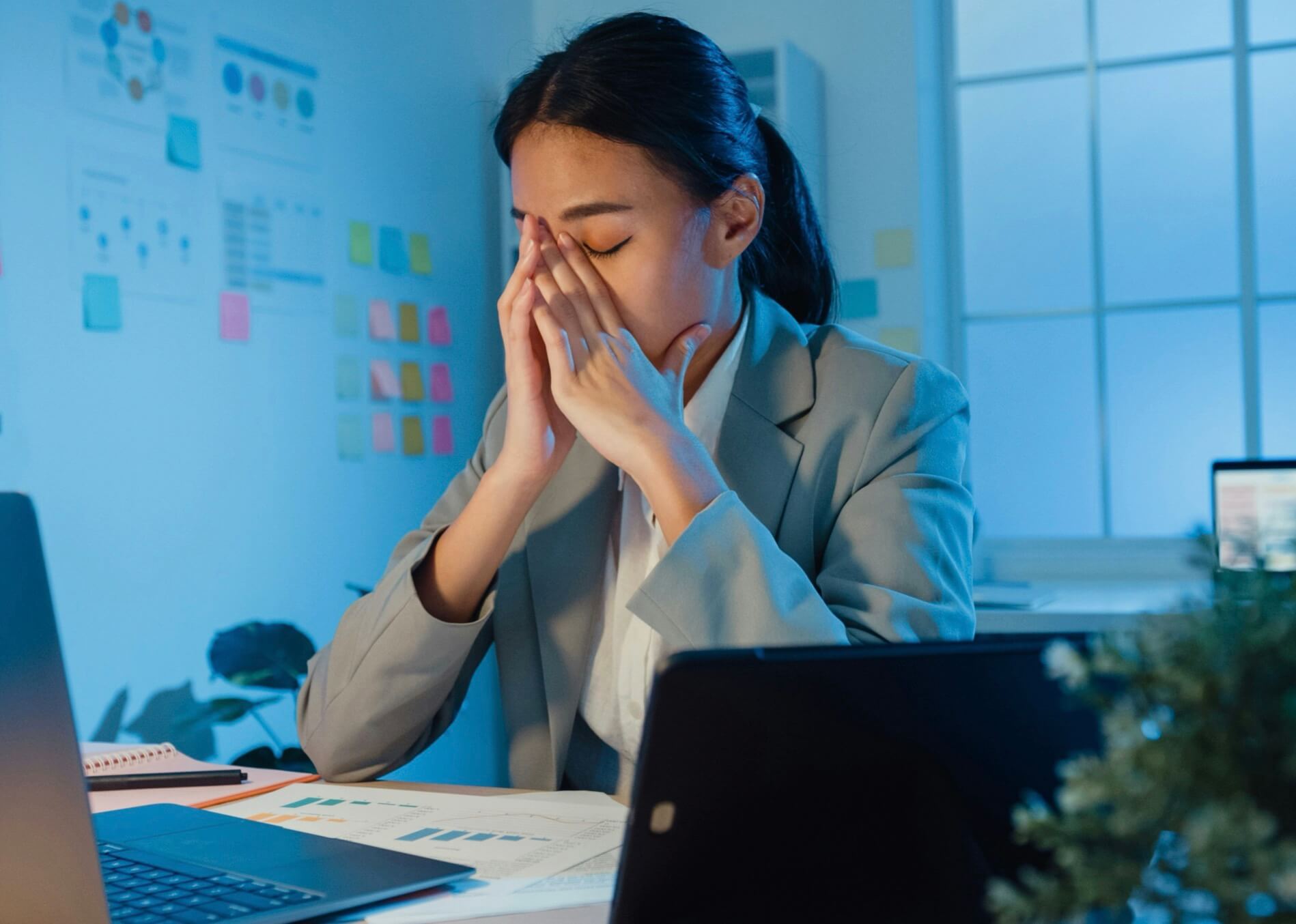 パソコンの前で目をおさえている女性の写真