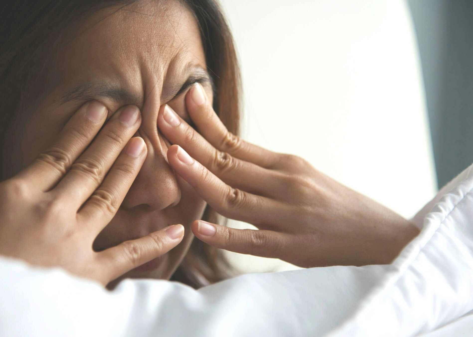 目の周りの筋肉が張って目をおさえている女性の写真