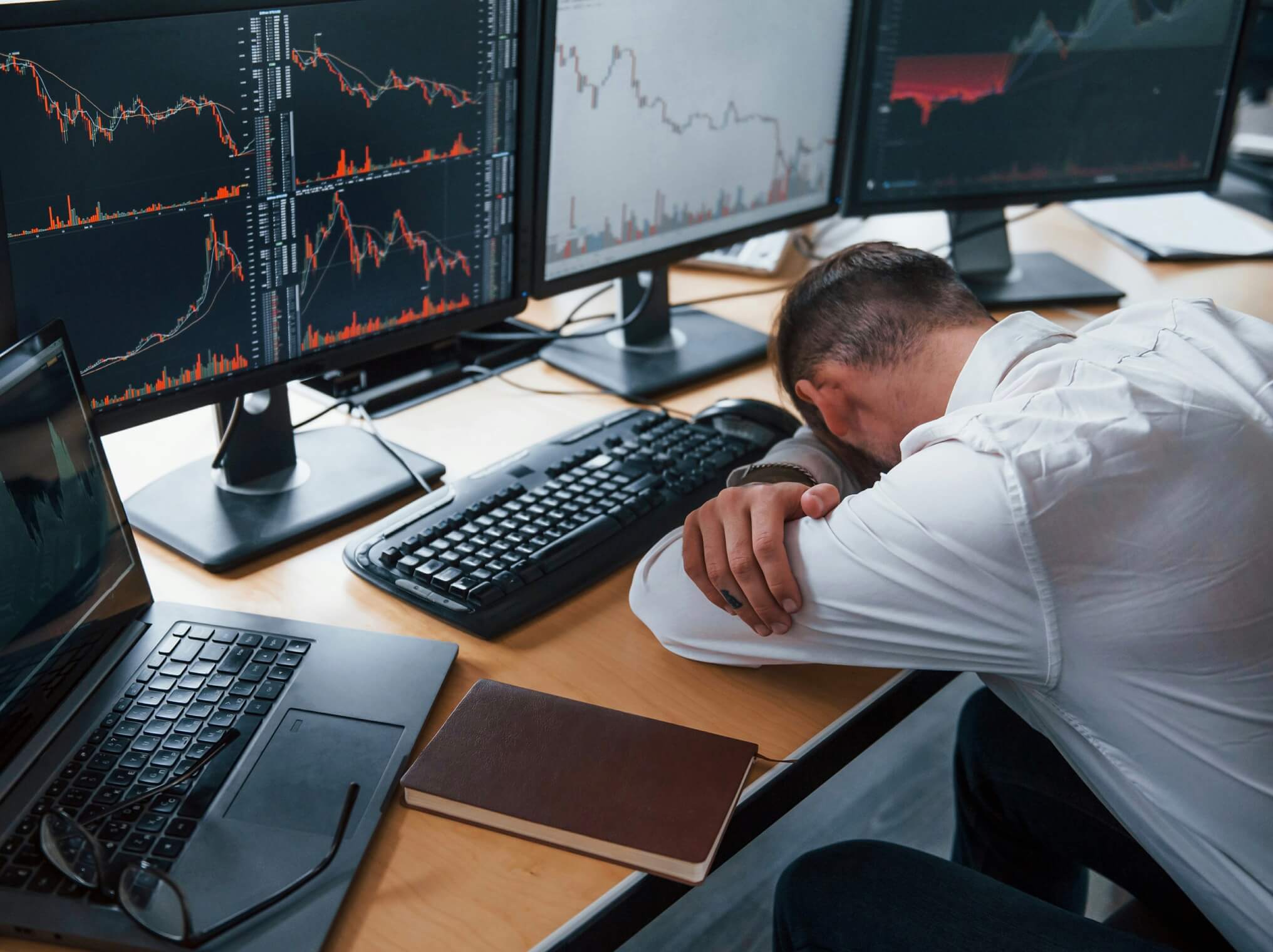 目が疲れてデスクで寝ている人の写真