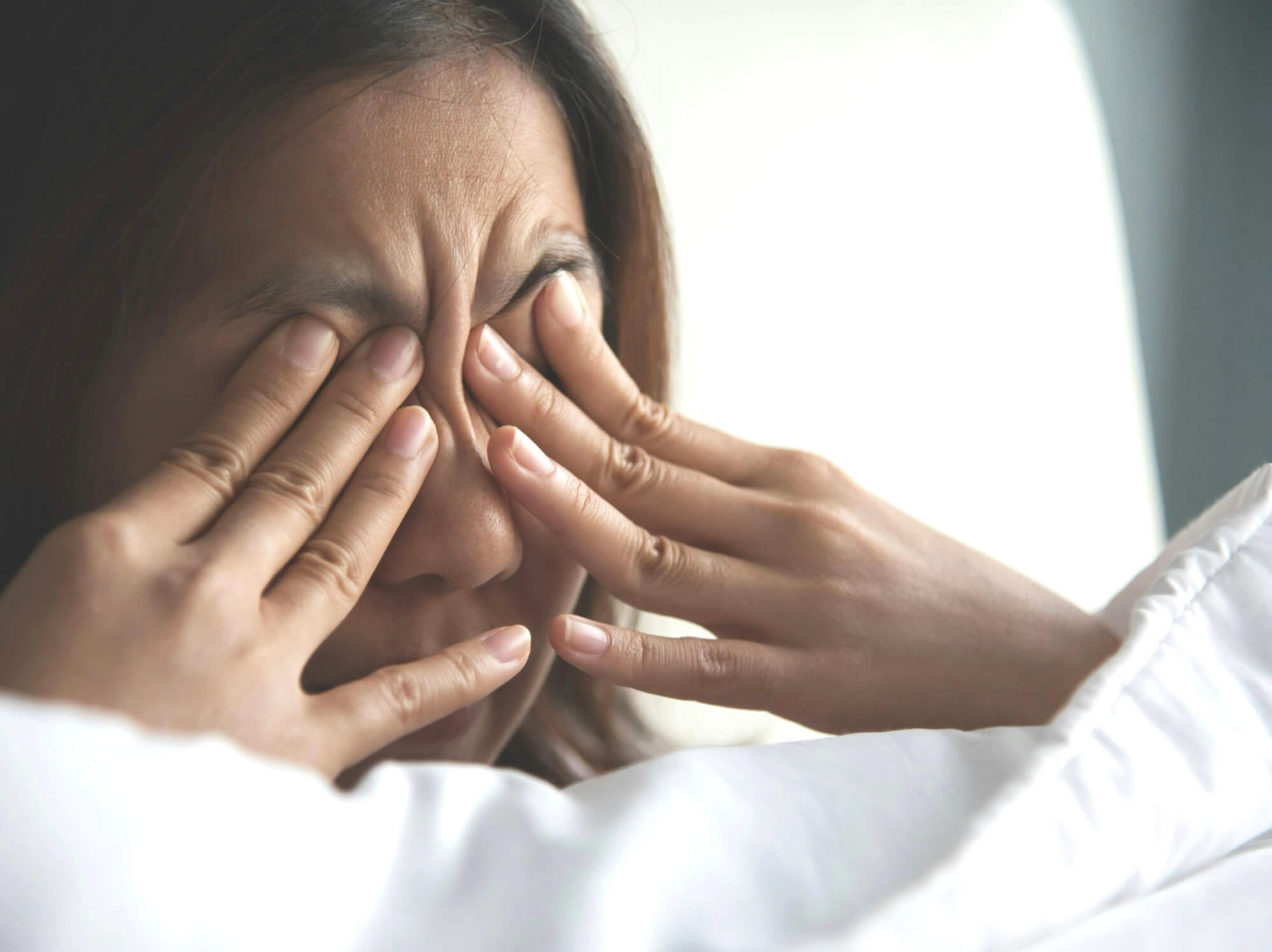 眠そうに目頭を抑えている女性の写真