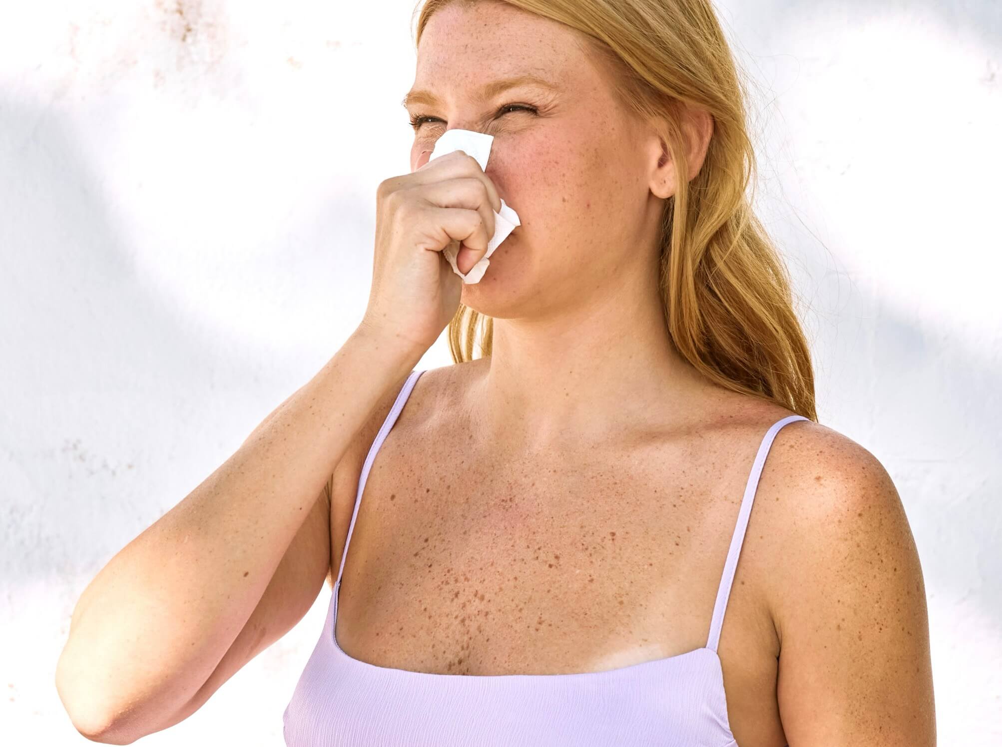 匂いで鼻を抑えている女性の写真