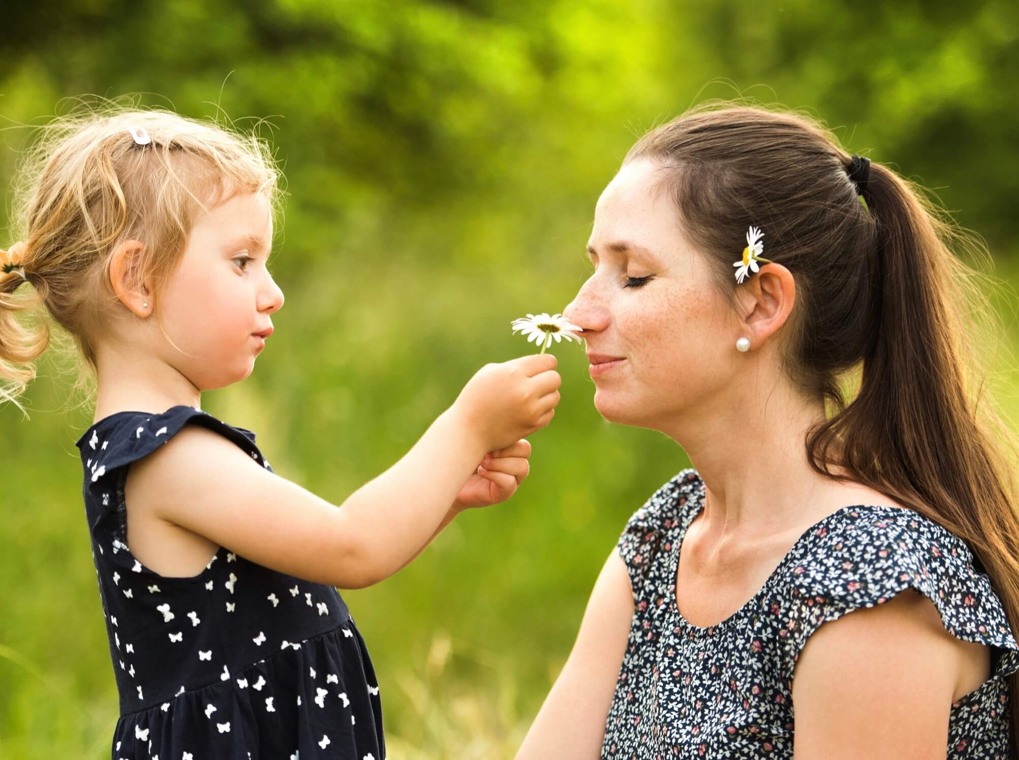 親子でお花の匂いをかいでいる写真