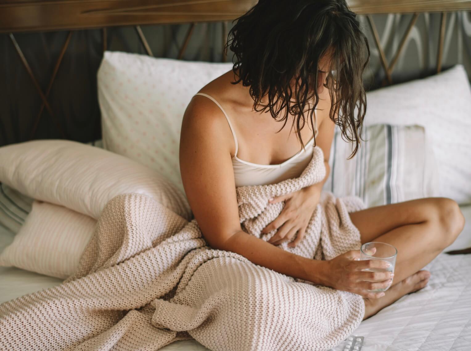 便秘薬を飲んでしんどそうな女性の写真